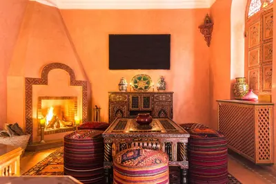 a living room with a fireplace and a table and chairs at Riad Tahyra in Marrakech