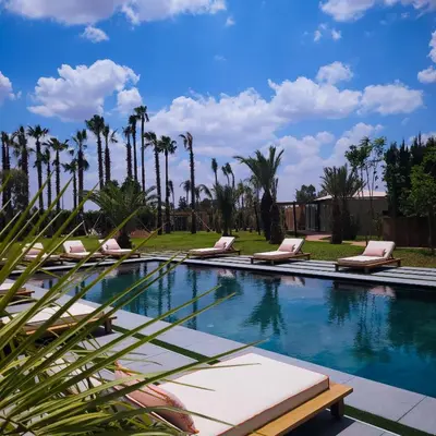 a swimming pool with lounge chairs and palm trees at Villa Oxygène Marrakech in Marrakech