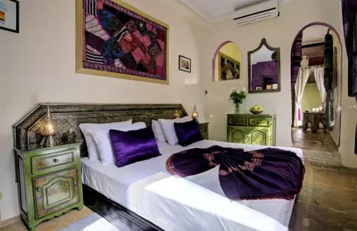 a bedroom with a large bed with purple pillows at Riad Dar El Souk in Marrakech