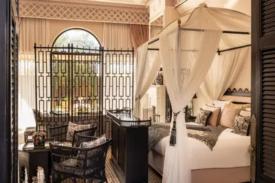 a bedroom with a canopy bed with a desk and chairs at Palais Ronsard Relais & Chateaux in Marrakech