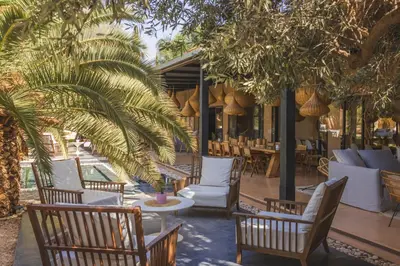 a patio with chairs and tables and palm trees at Villa Taj Marrakech in Marrakech