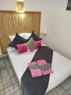 a bed with pink and black pillows on it at Riad Bab Lakhmiss in Marrakech