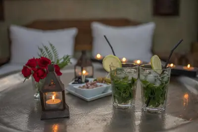 a table with two glasses and candles and a plate of food at Riad Le Limoun and Spa in Marrakech