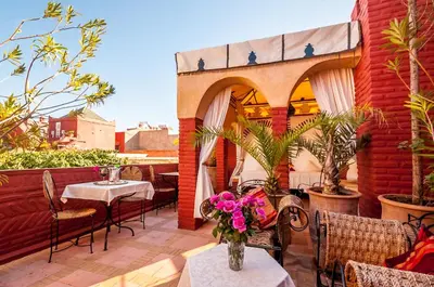 a patio with a table and chairs and a balcony at Riad Eden in Marrakech