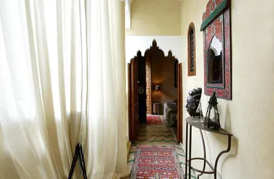a hallway with white curtains and a table with a rug at Riad Eden in Marrakech