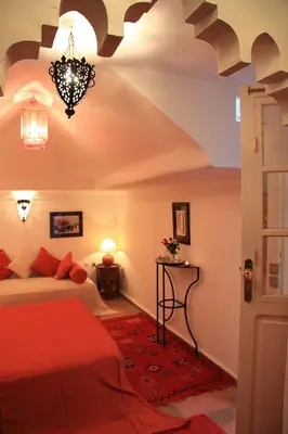 a bedroom with a red bed and a chandelier at Riad Eden in Marrakech