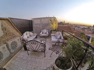 a balcony with two chairs and tables on a balcony at Riad L'Evidence in Marrakech