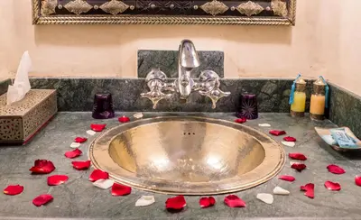a bathroom sink with red rose petals on the counter at Riad L'Evidence in Marrakech