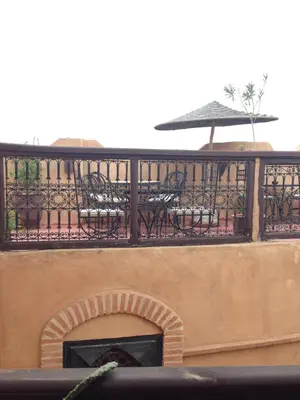 a balcony with chairs and a table and an umbrella at Riad Hiba in Marrakech
