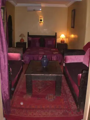 a bedroom with two beds and a table and a couch at Riad Hiba in Marrakech