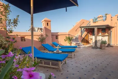 a patio with blue lounge chairs and flowers at Riad Khalifa in Marrakech