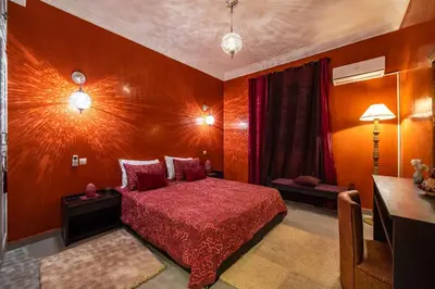 a bedroom with a red bed and a table at Riad Appart Arwa in Marrakech