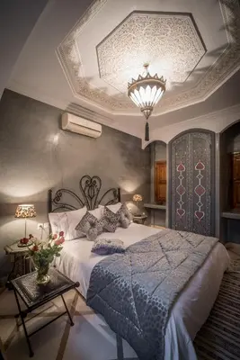 a bedroom with a large bed and a chandelier at Riad Dar Attika in Marrakech