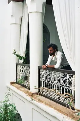 a man sitting on a balcony looking out the window at Riad Tizwa Marrakech in Marrakech