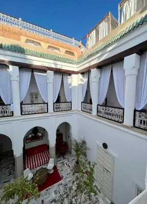 a large white building with windows and red chairs at Riad Tizwa Marrakech in Marrakech
