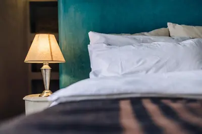 a bed with a table with a lamp on it at Riad Tizwa Marrakech in Marrakech