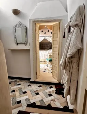 a hallway with a mirror and a doorway into a room at Riad Tizwa Marrakech in Marrakech