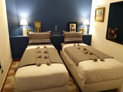 two beds in a room with blue walls at Riad BILKIS in Marrakech
