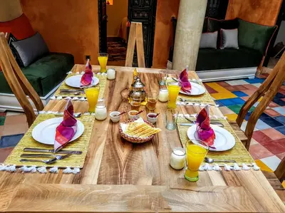 a wooden table topped with plates and glasses of orange juice at Riad BILKIS in Marrakech