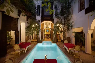 a large swimming pool in a building with tables and chairs at Riad Lyla in Marrakech