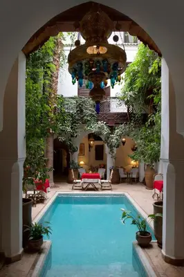 a pool in a courtyard with an archway and a house at Riad Lyla in Marrakech