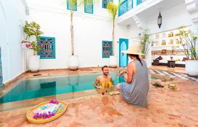 a woman standing next to a man in a swimming pool at Riad Chamali in Marrakech