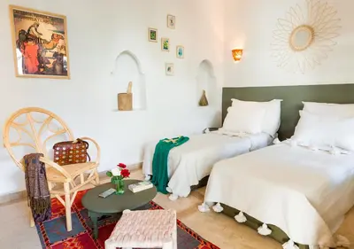 a bedroom with two beds and a chair at Riad Chamali in Marrakech