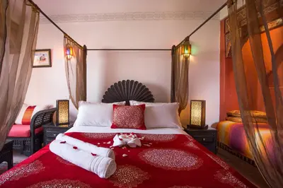 a bedroom with a large bed with a red blanket at Riad Jnane Mogador in Marrakech