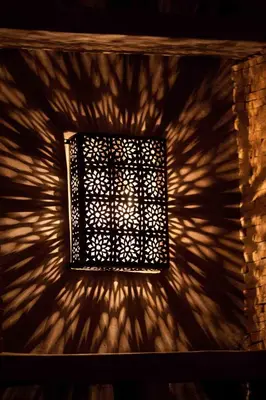 a light fixture on a wall with a shadow at Riad Shambala in Marrakech
