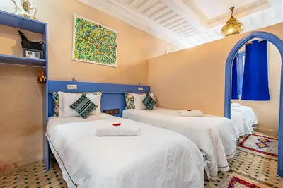 a room with three beds with white sheets at Maison KA in Marrakech