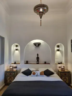 a bedroom with a large bed and a chandelier at Riad les Rêves d'Amélie in Marrakech
