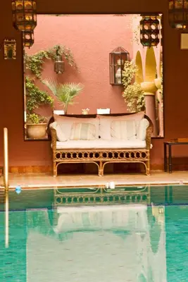 a couch is sitting next to a swimming pool at Riad Noga in Marrakech