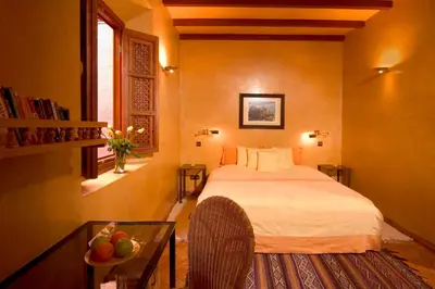 a bedroom with a bed and a table and a window at Riad Noga in Marrakech