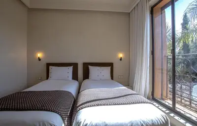 two beds sitting in a room with a window at Villa Atlas de Luxe avec piscine privée Domaine des Kasbahs in Marrakech