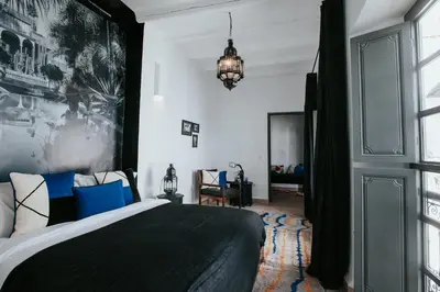 a bedroom with a large bed with blue pillows at Dar Titrit in Marrakech