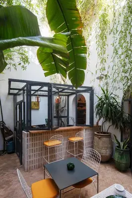 a patio with a table and chairs and plants at Dar Titrit in Marrakech