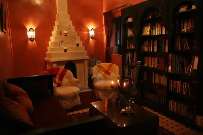 a living room with a fireplace and a book shelf filled with books at Riad Dar Zampa in Marrakech