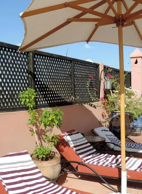 a group of chairs and an umbrella on a balcony at Riad Dar Zampa in Marrakech
