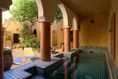 an indoor pool in a house with columns and a swimming pool at Ryad El Borj in Marrakech