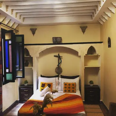 a bedroom with a bed with a cross above it at Riad Maison Aicha in Marrakech