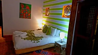 a bedroom with a bed with a green and white striped wall at Riad Rêve d Antan in Marrakech