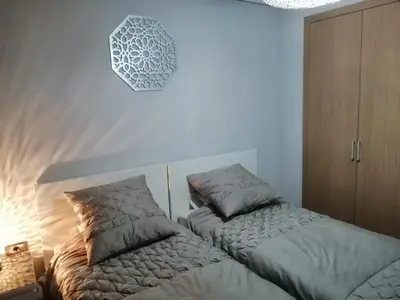 a bedroom with two beds and a clock on the wall at Prestigia Marrakech Village Appartment in Marrakech