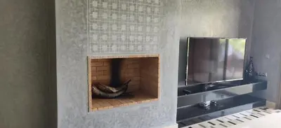 a brick fireplace with a television on a wall at Magnifique appart vue sur golf in Marrakech