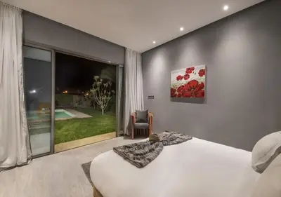 a bedroom with a bed and a large window at Palms Edge Villas avec Piscine & Jardin Privés in Marrakech