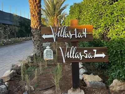 a sign for a resort with two arrows on it at Palms Edge Villas avec Piscine & Jardin Privés in Marrakech