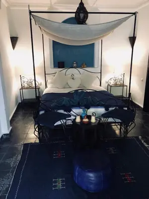 a bedroom with a bed with a canopy and two chairs at Riad Bjoujna in Marrakech