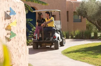 a man and woman sitting in a golf cart at Oasis lodges in Marrakech