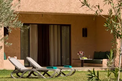 two chairs and a table in front of a house at Oasis lodges in Marrakech