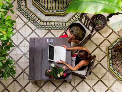 two women sitting at a table with a laptop at Riad Orange in Marrakech