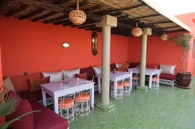 a restaurant with tables and chairs in a red wall at Riad Orange in Marrakech